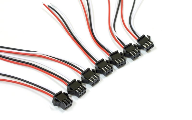 Seven three-pin connectors with red, white, and black cables coming out of them laying on a plain, white surface.