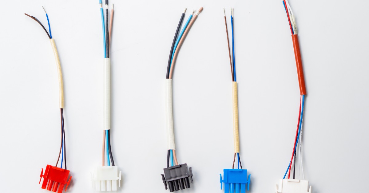 A red, black, blue and two white electrical connectors with wires connected to them are laying on a white background.