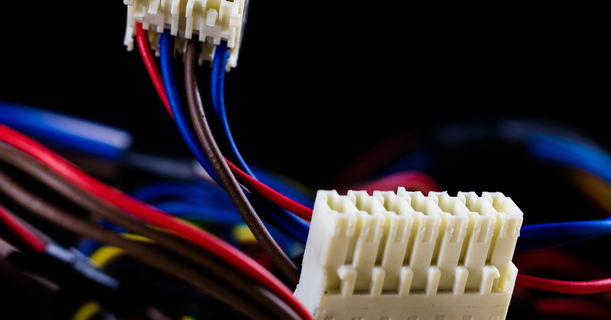 Two white automotive pin connectors with several terminals and blue, red, and black wires connected to their backs.