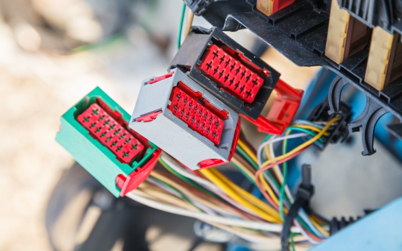 Several multi-cavity connectors from a vehicle's electrical system. Multiple colored wires are coming out the back of them.