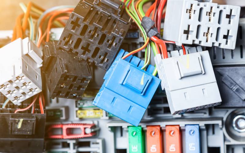 An assortment of differently colored electrical connectors and wires. Most are black or gray except for a blue one in the center.