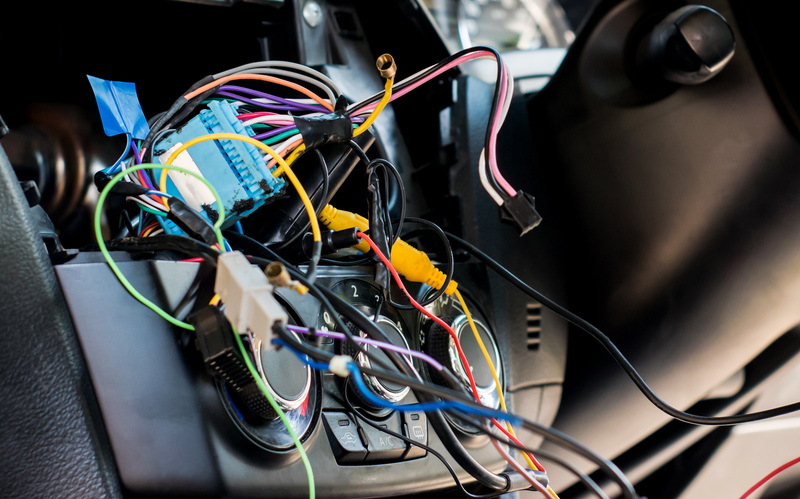 Multicolored wires connected to blue, black, and white connectors sticking out of a car&rsquo;s electrical system.