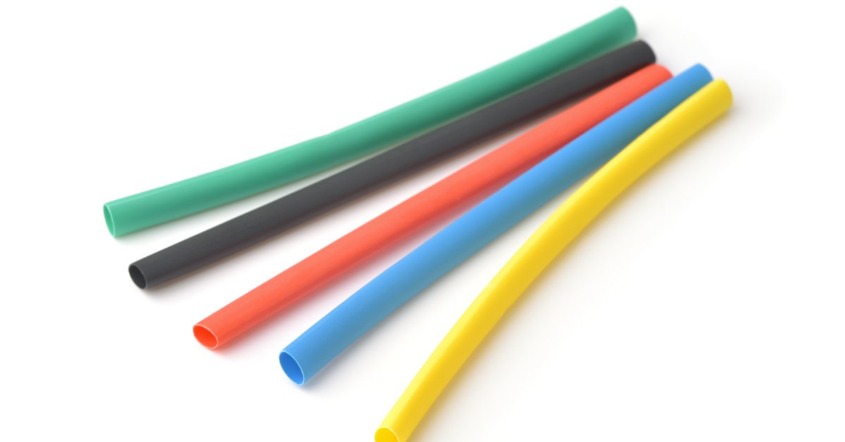Pieces of green, black, red, light blue, and yellow heat shrink tubing laying on a white surface.
