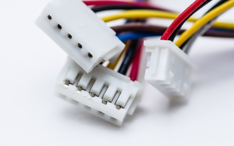 Three white electrical connectors with colorful wires coming out of them are sitting on a white surface.