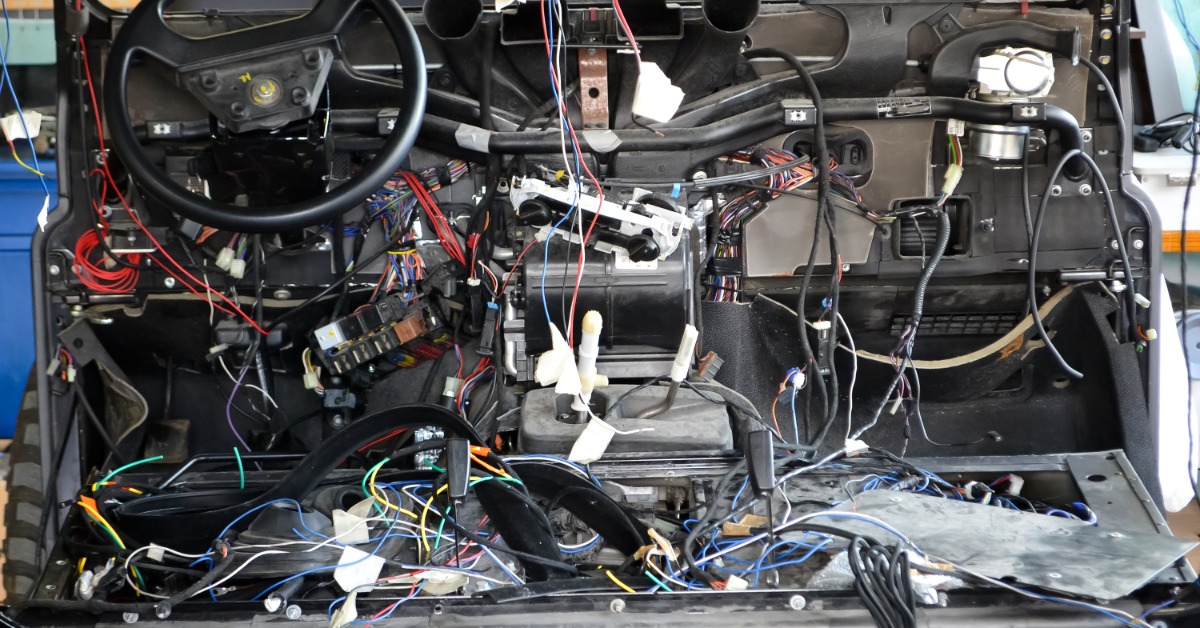 A car interior with its dashboard dismantled to expose wires underneath. The steering wheel is still in the vehicle.