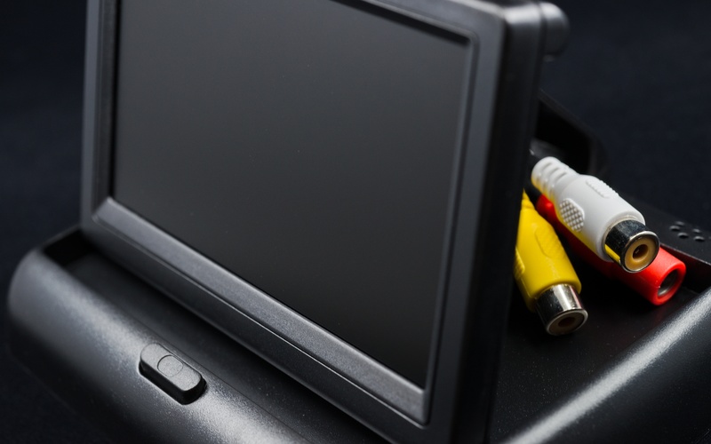 A person sitting in the driver's seat in a car tapping the touchscreen GPS on top of their dashboard.