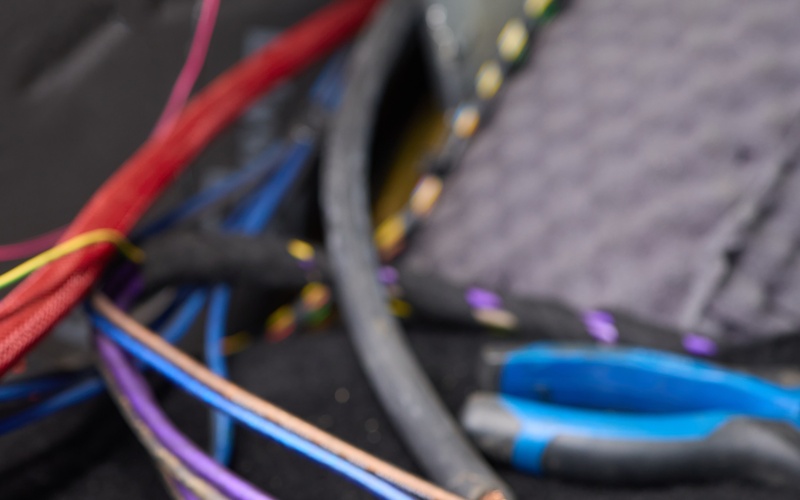 Purple, beige, and orange wires with metal ends lie on the floor of a car. Extra wires are visible in the background.